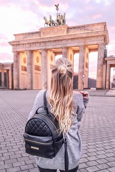 a woman with blonde hair is taking a selfie in front of the berlin skyline