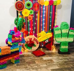 brightly colored paper decorations are on display in front of a wall with cactuses and lights