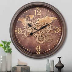 a large clock with gears on the face is displayed in front of a white wall