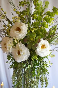 a vase filled with white flowers and greenery