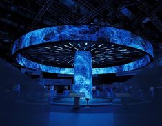 a large circular structure with blue lights in the center and an abstract design on it