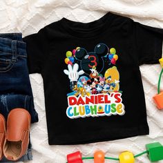 a black shirt with mickey mouse's club house on it next to some toys