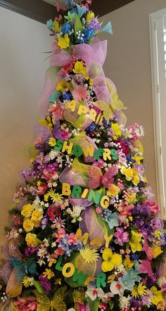 a very colorful decorated christmas tree with flowers on it's sides and the words happy new year written in large letters