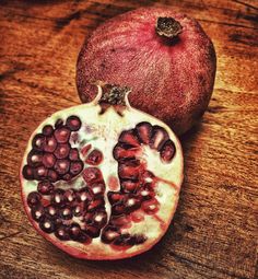 a pomegranate cut in half sitting on top of a wooden table