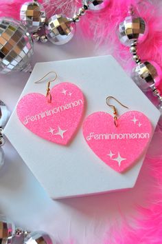 You're a femininomenon, babe! Laser-cut acrylic earrings engraved and hand-painted with the iconic word and song title "Femininomenon" on the most gorgeous hot pink neon sparkly acrylic, and finished with hypoallergenic gold-plated stainless steel fish hooks for closure. Materials: acrylic, gold-plated stainless steel hardware Measurements: 2.5" drop length, 2.1" width, .4oz weight Chappell Roan Earrings, Acrylic Earrings Laser Cut, Neon Jewelry, Midwest Princess, Bumper Magnets, Earring Inspo, Hair Necklace, Chappell Roan, Fish Hooks