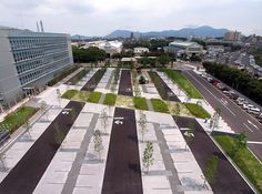 an aerial view of a parking lot in the middle of a city with trees and grass