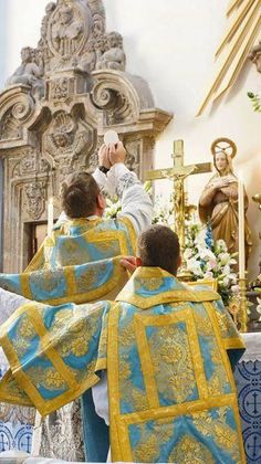 two men in blue and yellow robes kneeling down at the alter with their hands together