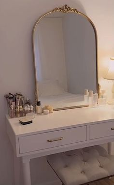 a white vanity with a large mirror and lots of cosmetics on it's drawers