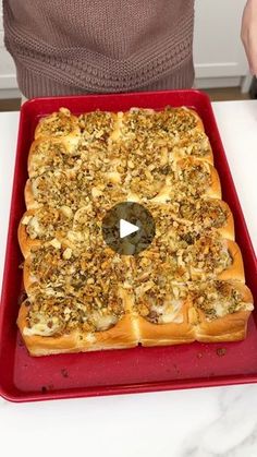 a person holding a red tray filled with bread and toppings on top of it