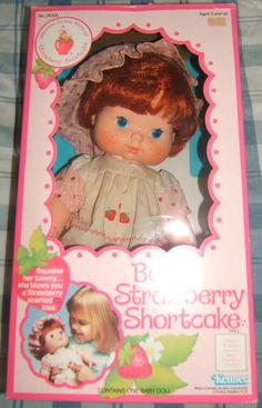 the doll is in its box and it has strawberry shortcakes on her head