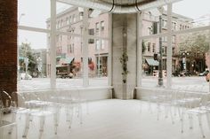 chairs are set up in front of large windows on the side of an empty street