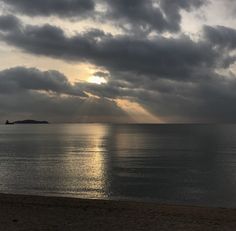 the sun is shining through clouds over the ocean