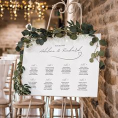 the seating chart for an outdoor wedding is displayed on a easel with greenery