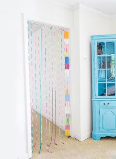 a blue china cabinet sitting in the corner of a room with streamers hanging from it