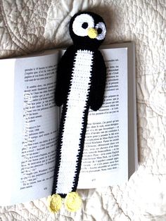 a crocheted penguin laying on top of an open book