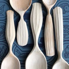 four wooden spoons are lined up on a blue tablecloth with an intricate design