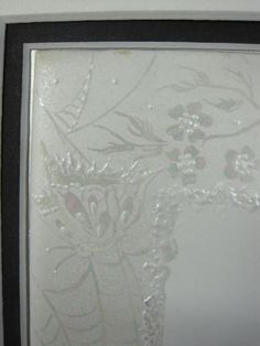 a white and black frame with some flowers on the glass in it's center