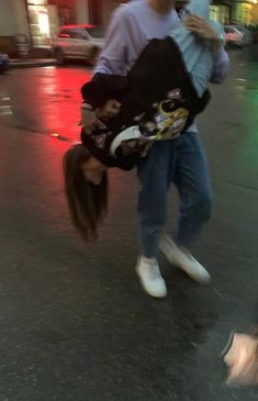 a man carrying a woman on his back while walking down the street in the rain