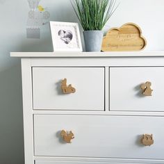 a white dresser with two drawers and a potted plant sitting on top of it