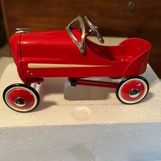 a red toy car sitting on top of a white table