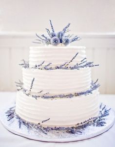 a white wedding cake with lavender sprigs on top and the words, wedding cakes lavender