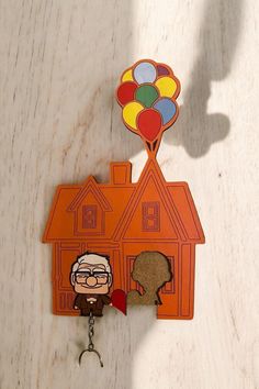 a house keychain with an image of a man holding balloons on top of it