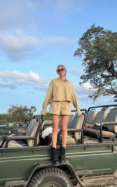 a woman standing on the back of a green truck