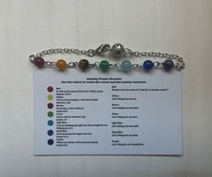 a bracelet with seven chakras on it and a chain attached to the clasp