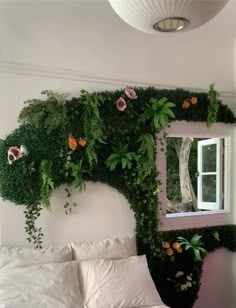 a bed with white sheets and pillows covered in greenery next to a window filled with flowers