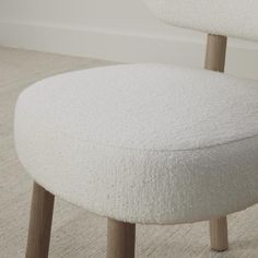 an upholstered white chair with wooden legs in a living room or dining room