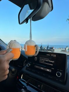 two orange balls hanging from the dashboard of a car, being held by someone's hand