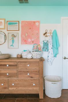 a wooden dresser sitting next to a white door in a room with pictures on the wall