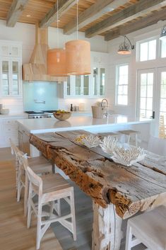 a large wooden table sitting in the middle of a kitchen next to an island with chairs