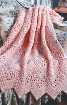 a pink crocheted blanket sitting on top of a bed