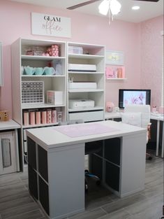 a pink and white room with lots of shelves, desks, and other items