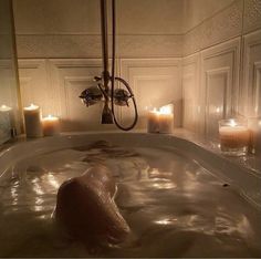 a bathtub filled with lots of water next to candles