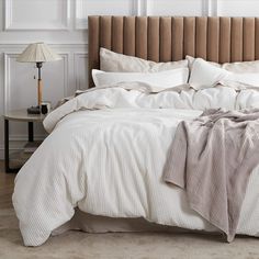 an unmade bed with white sheets and pillows