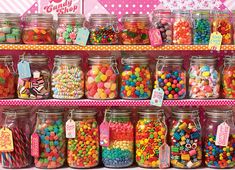 many jars filled with different types of candy and candies on display in front of a pink polka dot wall