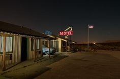 the motel is lit up at night with an american flag flying in the sky above it