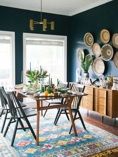 a dining room table with chairs and plates on the wall in front of it's windows