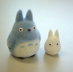 two small toy animals sitting next to each other on a white counter top with one animal looking at the camera