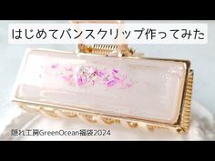 a pink and gold purse with flowers on it's front, sitting on top of a white doily