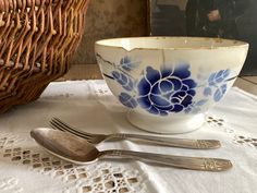 a blue and white bowl sitting on top of a table next to two silverware