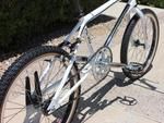 a bicycle parked on the side of a road next to a bush and sidewalk area