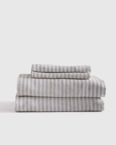 three striped sheets are stacked on top of each other in grey and white linens