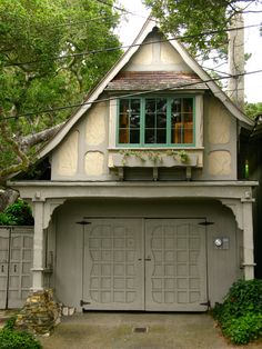 a house with two garages in the front and one on the other side that has green shutters