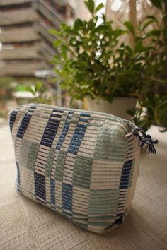 a close up of a pillow on a table near a potted plant and building