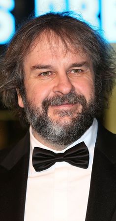 a man in a tuxedo and bow tie smiles for the camera at an event