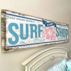 a surf shop sign hanging on the wall above a bed