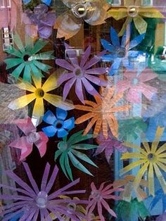 colorful paper flowers are displayed in a window